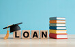 © Aminograpix - Student loan and college tuition debt concept, featuring a graduation cap on wooden blocks and a stack of books, representing education financing.