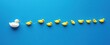 © Mann - One white rubber duck leading the way for a group of yellow ducks on a blue background, a minimalist conceptual photograph.