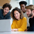 © Juiy - Diverse team gathered around laptop, discussing project with lively expressions, showcasing teamwork and collaboration in modern office setting