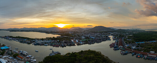Wall Mural - A breathtaking view of a vivid yellow, pink and purple sunset reflecting on calm sea. This serene scene captures the beauty of nature's colors at Phuket fishing port. colorful cloud scape background
