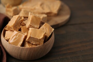 Wall Mural - Homemade caramel candies in bowl on wooden table, closeup. Space for text