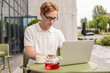 © zinkevych - Ginger male freelancer checking emails using laptop in street cafe