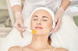 © elenavolf - Female caucasian adult receiving facial treatment at spa with relaxed expression and brush application.