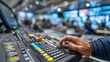 © Justlight - Technicians hand operating the intercom system medium shot with the communication panel in sharp focus and the busy broadcast control environment blurred.