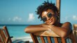 © Johannes - portrait of happy young black woman relaxing on wooden deck chair at tropical beach while looking at camera wearing spectacles smiling african american girl with fashion sunglasses enjoying vacation