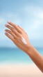 © Marin Zhu - Beautiful hand with a creamy lotion applied, showcasing skincare routine against a serene beach backdrop with soft waves and a clear blue sky, emphasizing relaxation and self-care