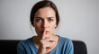 © Hasbian - A serious young woman makes a shush gesture, emphasizing the need for quiet, confidentiality, or discretion in a moment of seriousness.