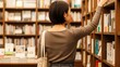 © AiPhoto - 書店で本を選ぶショートヘアの女性の後ろ姿