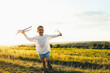 © shine.graphics - Happy boy running across field at sunset holding toy airplane and flowers, carefree childhood moment of joy, freedom and play in summer nature