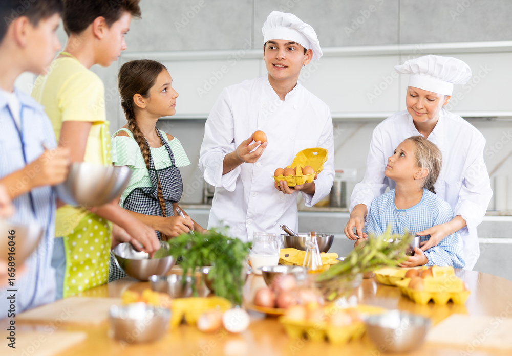 During lesson in cooking courses, male cook professional tells children ...