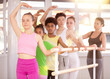 © JackF - Motivated cute girl participating in beginner ballet class for teenagers with female teacher, learning third position at barre in light dance studio..