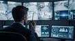 © dreamdes - Male security officer monitoring multiple CCTV feeds in control room. Surveillance specialist or dispatcher on duty for public safety.
