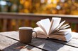 © oksa_studio - Open book and coffee cup resting on wooden table in autumn with blurred background of colorful trees