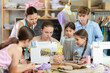 © JackF - Female teacher demonstrates how to sew on a sewing machine. Children gather around and watch