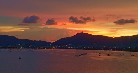 Wall Mural - Aerial view of A tranquil sunset over a calm coastal landscape, with colorful sunset behind distant mountains and reflecting on the sea.The serene water create a peaceful and atmospheric view