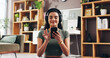 © peopleimages.com - Headphones, phone and woman in home for fitness, podcast and listening to audio online. Mobile, smile and girl with music for exercise album, sound and streaming radio for pilates in living room