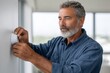 © SerPak - A mature man with a beard adjusts a smart thermostat in a contemporary living space, showcasing home technology and comfort.