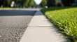 © abba - A low angle view of a sidewalk with green grass and asphalt road in the background.