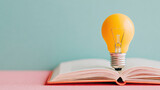 Open book with pages fanned out, featuring a glowing yellow light bulb placed on top, symbolizing creativity and inspiration in a vibrant, colorful setting