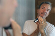 © Laura - Mature man shaving in front of a mirror with an electric razor