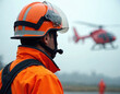 © Pete - Emergency responder in bright orange uniform and helmet observes red helicopter. High-visibility safety gear worn. Teamwork during disaster response operation, preparedness for rescue mission.
