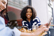 © Westend61 - Happy young woman using mobile phone with friend at cafe