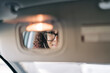 © Studio Marmellata - A woman with curly hair and glasses is reflected in a car's rearview mirror. Her eyes are visible through the glasses as she looks directly into the mirror.