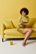 © LIGHTFIELD STUDIOS - Curly woman in yellow outfit engages with gadget in vibrant studio space