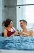 © Zoran Zeremski - Middle aged couple relaxing in hot tub at spa and drinking champagne.