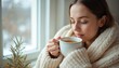 © Pete - Young woman drinking hot tea, wrapped in warm blanket at home near window during cold season. Female with closed eyes enjoys comfort, cosiness and rest. Sick girl recovery with herbal teacup.