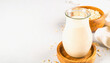 © PHAISITSAWAN - A clear glass of homemade oat milk next to a wooden bowl filled with oats isolated on a bright white background