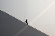 © DragonImages - Caucasian young adult man walking down large staircase in minimalist setting, business attire suggesting professional context, side profile visible, empty background emphasizing scale