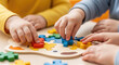 © SATEAYAM - Young Children's Hands Playing with Colorful Jigsaw Puzzle on Wooden Table Educational Game Enhancing Fine Motor Skills and Cognitive Development in Early Childhood