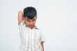 © Mdv Edwards - A young Asian boy grimacing as he scratches his back, struggling to reach and appearing uncomfortable and slightly annoyed. Isolated on a white background.