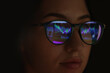 © New Africa - Young woman wearing glasses with reflection on dark background, closeup