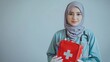 © ikrar.project - A professional Muslim woman doctor wearing a hijab and a lab coat, holding a first aid kit with a caring and trustworthy expression.