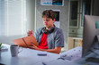 © PaeGAG - Focused young man working or studying from home taking notes in his notebook while sitting at his desk