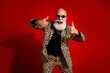 © deagreez - Fashionable older man in leopard print suit posing with a confident thumbs up gesture on bright red background