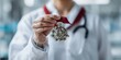 © Julian  - A healthcare professional, likely a doctor or researcher, holds a complex, metallic medal against a blurred background.