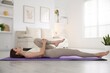 © New Africa - Young woman in sportswear stretching on mat at home