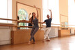 © New Africa - Couple of professional dancers stretching at barre in studio
