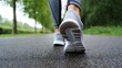 © Fatma - Close up of a person s feet in athletic shoes walking on a wet asphalt path lined with green trees and foliage on a cloudy day
