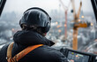 © thodonal - Construction worker operating a crane overlooking a city skyline