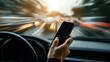 © Shelley - A person holding a smartphone while driving, with a blurred road background and space for copy, highlighting the importance of safety and responsible mobile use on the road.