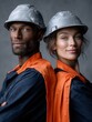 © Tima - A young African man and a young Caucasian woman stand back to back, both wearing silver helmets and orange safety vests. They display confident expressions.