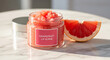 © Aizazul - Grapefruit lip scrub in a jar with a slice of grapefruit on a marble surface