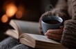 © oksa_studio - Woman wearing a knitted sweater is holding a steaming mug and reading a book by the fireplace, enjoying a cozy winter evening