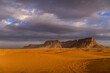 © Artaxerxes - Near Riyadh, Saudi Arabia: sunbaked desert floor speckled with acacia shrubs extends to a flat-topped mesa, amid scattered debris.