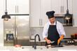 © Volodymyr - Chef in uniform cooking raw fish salmon fillet in the kitchen. Restaurant menu concept. Male chef in working uniform, black apron, chef hat. Fish salmon concept.
