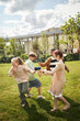 © DragonImages - Group of multiethnic children playing with bubble machine on grass, laughing and running outdoors, two girls and two boys interacting energetically in park setting
